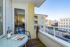 A balcony with a glass table, a chair, a bottle of water, and a magazine.