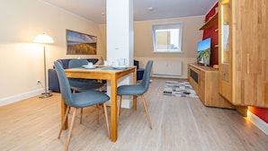 Een moderne keuken met houten kastjes, een eethoek met een tafel en stoelen, een staande lamp en een raam met uitzicht.