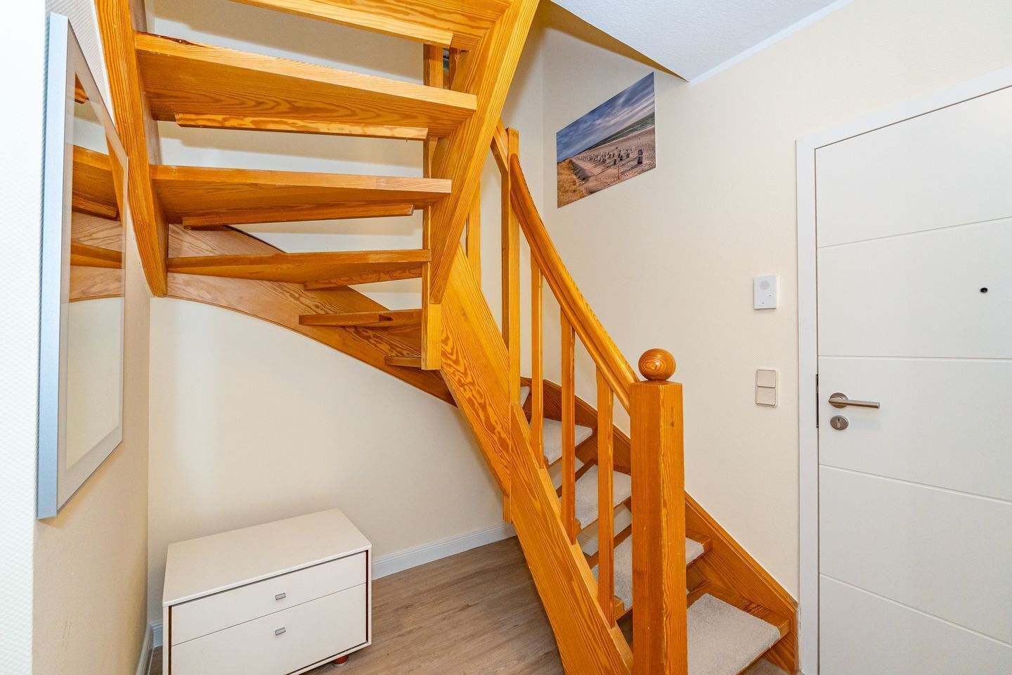 Una escalera de madera con una puerta blanca y un pequeño armario blanco.