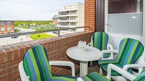 Een balkon met twee streepstoelen, een klein rond tafeltje en een witte lantaarn.