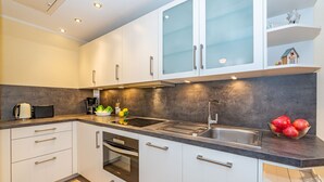 Een moderne keuken met witte kasten, een roestvrijstalen spoelbak en een ingebouwde oven.