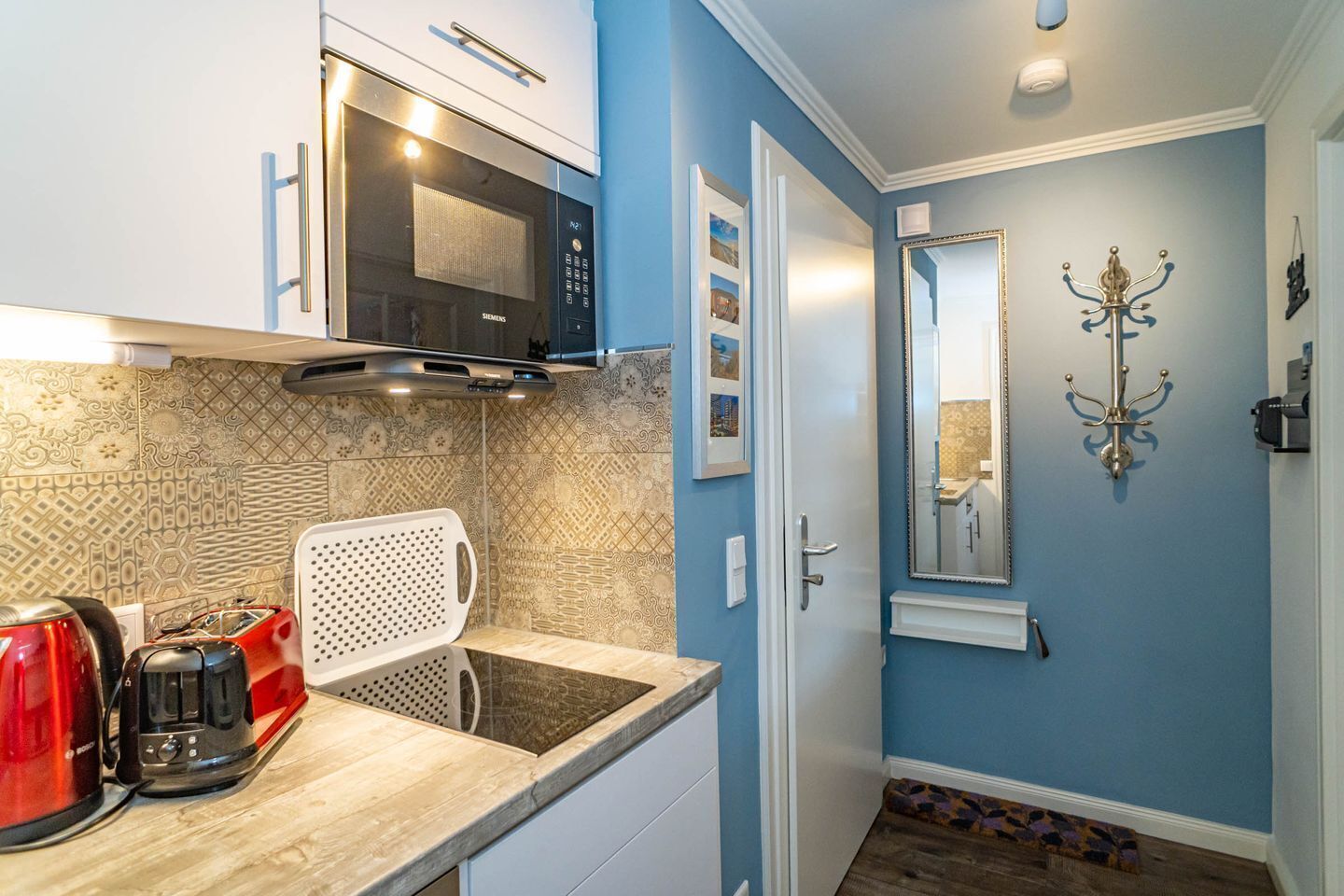 A compact kitchen with a microwave, toaster, and kettle on the counter.