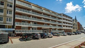 A multi-story hotel with balconies, a parking lot, and a clear blue sky. - Strandmuschel App. 309 - Kleine, Geschmackvoll Eingerichtete Wohnung in Westerland, Direkt am (Sylt)