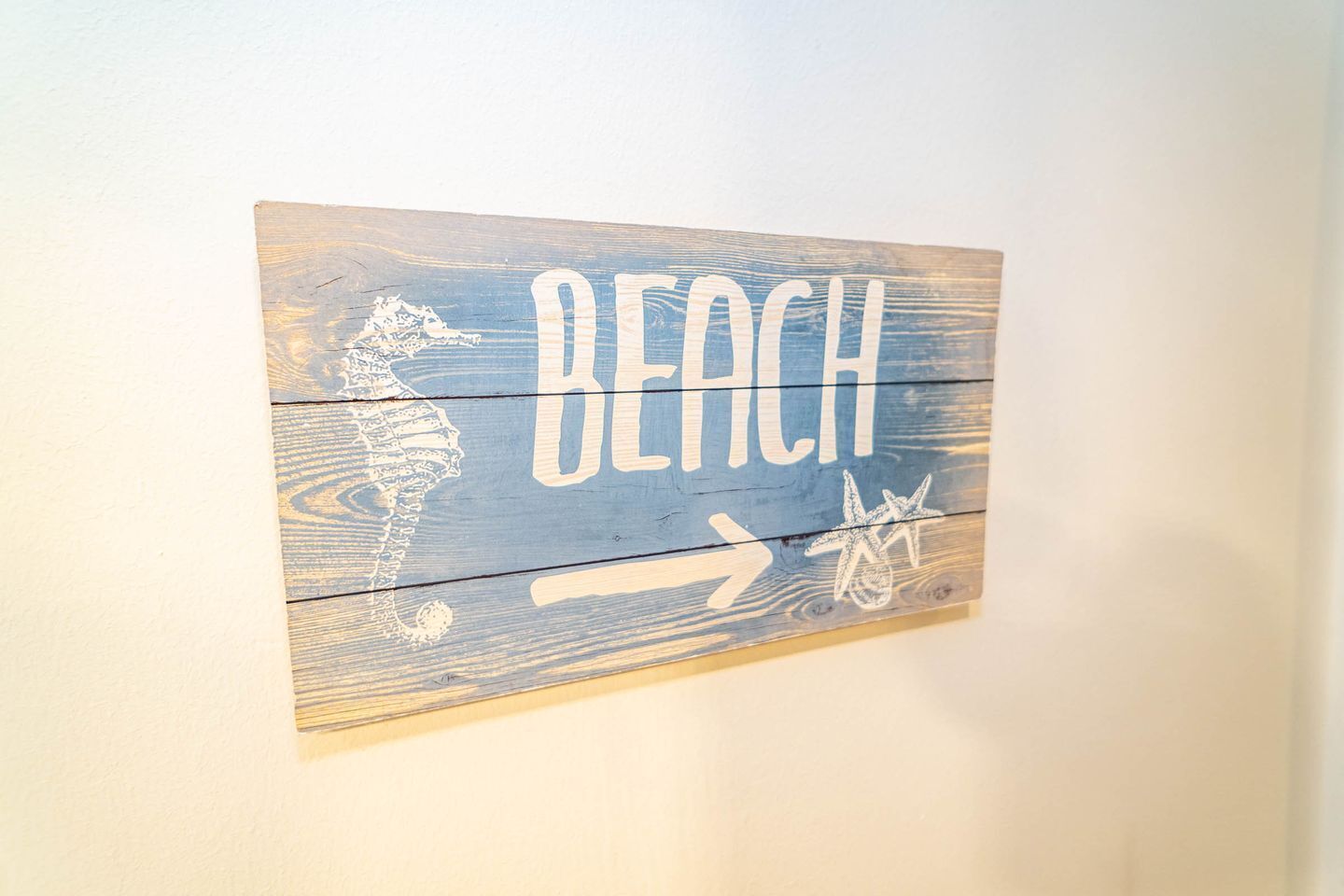A wooden sign with the word "BEACH" and a seahorse and starfish illustration.