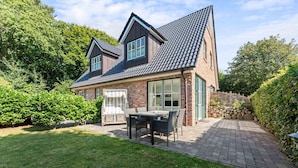 A two-story house with a brick exterior, a tiled roof, and a paved patio with outdoor furniture. - Wandaful Hüs - Holiday home for max. 4 persons, in a quiet location with (Sylt)