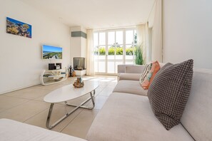 En moderne stue med sofa, sofabord, tv og pejs.