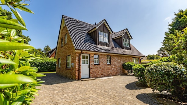 A two-story brick house with a steeply pitched roof, a front door, and a paved driveway. - Wandaful Hüs - Holiday home for max. 4 persons, in a quiet location with (Sylt)