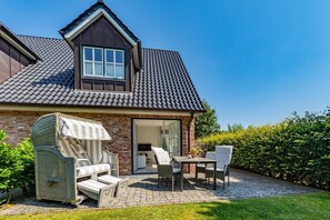 A house with a brick exterior, a tiled roof, and a patio with outdoor furniture.