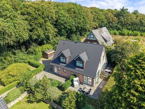 A house with a sloped roof, a brick exterior, and a paved patio with outdoor furniture.