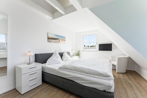 A modern bedroom with a bed, bedside table, lamp, and a painting on the wall.
