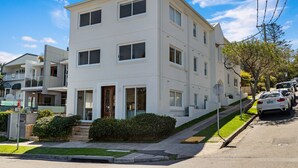 A multi-story residential building with a flat roof, large windows, and a front entrance with steps. - Little Manly 3 bedroom Oasis (Manly)