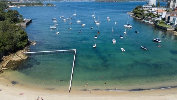 A coastal area with a sandy beach, a pier, and numerous boats in the water. - Little Manly 3 bedroom Oasis (Manly)