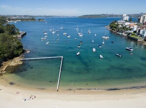 A coastal area with a sandy beach, a pier, and numerous boats in the water. - Little Manly 3 bedroom Oasis (Manly)
