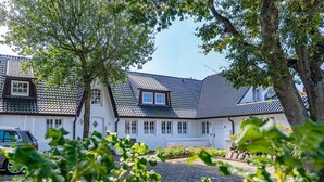 A traditional building with a tiled roof, white walls, and a paved courtyard. - Roseneck App. 6 - Cozy vacation apartment for up to 2 persons with (Sylt-Ost)