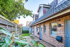 En boligejendom med murstensfacade, træhegn og en lille have.