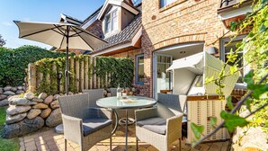 A patio with wicker furniture, a round table, and a large umbrella.