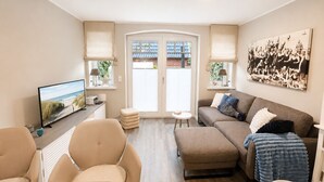 A living room with a television, sofa, chairs, and a dining table.