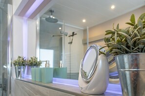 A bathroom vanity with a mirror, a potted plant, and a teal-colored soap dispenser. - App. Sonnenzauber - 1-room vacation apartment with balcony in Westerland, directly on the (Sylt)