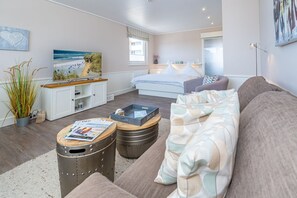 A modern living room with a bed, a sofa, and a dining area. - App. Sonnenzauber - 1-room vacation apartment with balcony in Westerland, directly on the (Sylt)