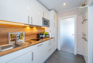 Une cuisine moderne avec des armoires blanches, un plan de travail en bois et un four à micro-ondes encastré.