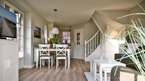 Eine geräumige Küche mit weißen Schränken, ein Essbereich mit einem weißen Tisch und Stühlen sowie eine Treppe, die zu einer anderen Ebene führt.