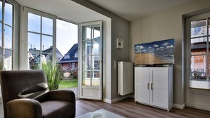 Ein Wohnzimmer mit einem braunen Ledersofa, einem weißen Tisch und einem Bild von einer Strandansicht.
