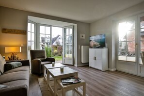 Una sala de estar con sofá, sillón, mesa de centro, televisor y aparador.