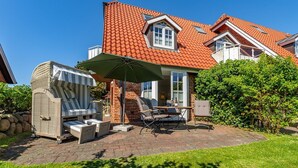Ein Haus mit roten Ziegeln, einer Ziegelaußenfassade und einer Terrasse mit Gartenmöbeln sowie einer überdachten Sitzgruppe.
