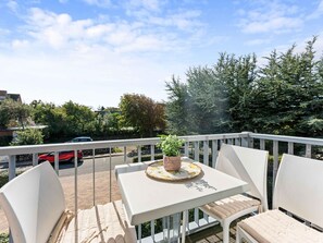 A balcony with a table, chairs, and a potted plant. - Syltmuschel - Relaxen Sie in der Wunderschönen und Neuen 3-zimmerwohnung in Westerland (Sylt)