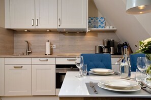 A modern kitchen with white cabinetry, a built-in oven, and a dining area with a table set for two.