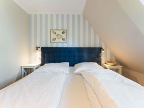 A bedroom with a bed, two bedside tables, and a wall-mounted artwork. - Syltmuschel - Relaxen Sie in der Wunderschönen und Neuen 3-zimmerwohnung in Westerland (Sylt)