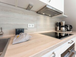 A modern kitchen with a stainless steel range hood, a coffee maker, and a bag on the counter.