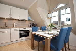 A modern kitchen with white cabinets, a wooden dining table, and blue chairs.