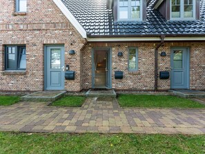 A brick house with a grey door, a mailbox, and a small front yard. - Syltmuschel - Relaxen Sie in der Wunderschönen und Neuen 3-zimmerwohnung in Westerland (Sylt)