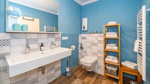 A bathroom with a white sink, a mirror, a toilet, and a towel rack. - Adlerhorst - Modern vacation apartment with large roof terrace and private sauna in (Sylt)