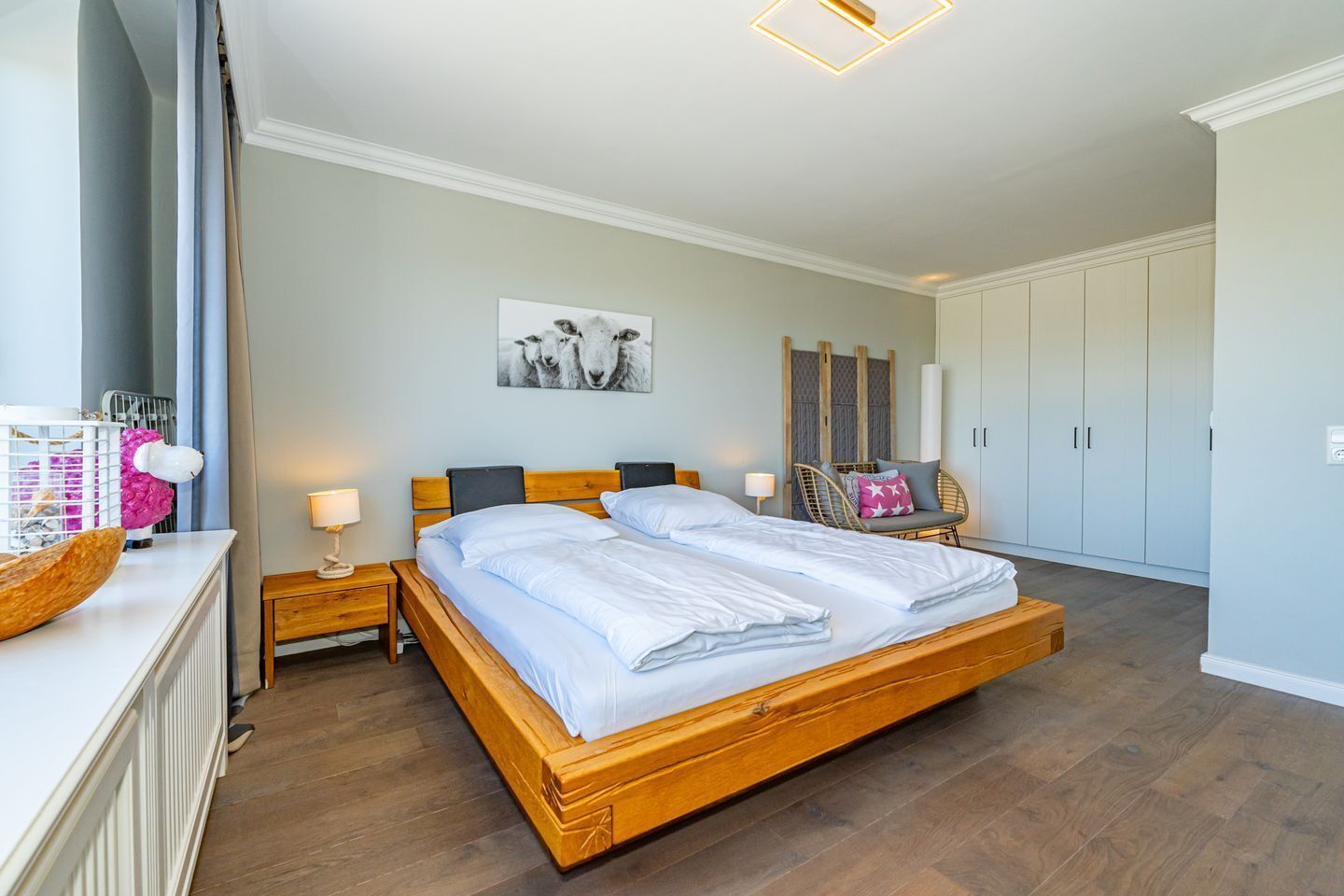 Ein Schlafzimmer mit einem hölzernen Bett, Nachttischen, einem Sessel und einem Kleiderschrank.
