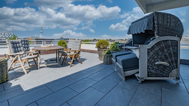 A rooftop terrace with a round table, two chairs, a grill, and potted plants. - Adlerhorst - Modern vacation apartment with large roof terrace and private sauna in (Sylt)