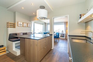 A modern kitchen with a central island, wooden cabinets, and a built-in seating area.