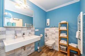 A bathroom with a white sink, a mirror, a toilet, and a towel rack.