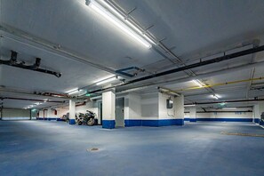 Eine überdachte Innenparkgarage mit zahlreichen Stellplätzen, Betonsäulen und Deckenleuchten.