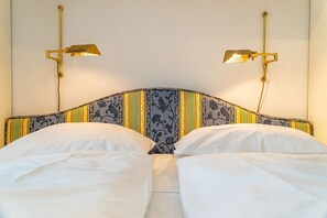 Una cama con cabecera a rayas y dos lámparas de pared.