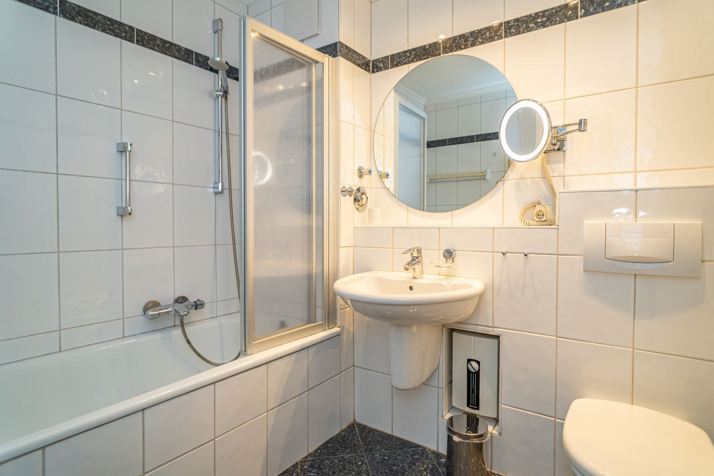 A modern bathroom with a glass-enclosed shower, a sink with a mirror, and a toilet.