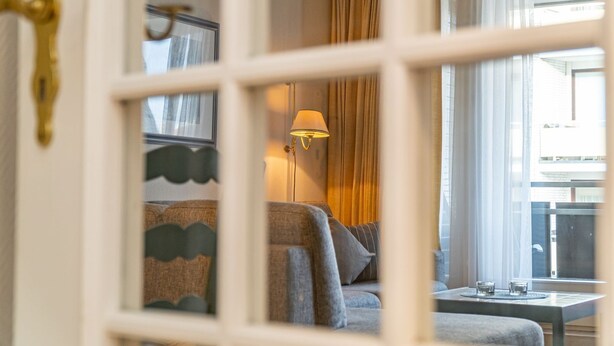 A hotel room with a sofa, a table with glasses, and a lamp. - App. Störtebeker App. 16 - Close to the beach & right in the city center. Vacation apartment for (Sylt)