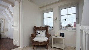 A cozy room with a wicker chair, a small white table, and a window with a view. - House Lotte - Holiday home for up to 6 people with garden. - only 450m to the (Sylt)