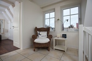 A cozy room with a wicker chair, a small white table, and a window with a view.