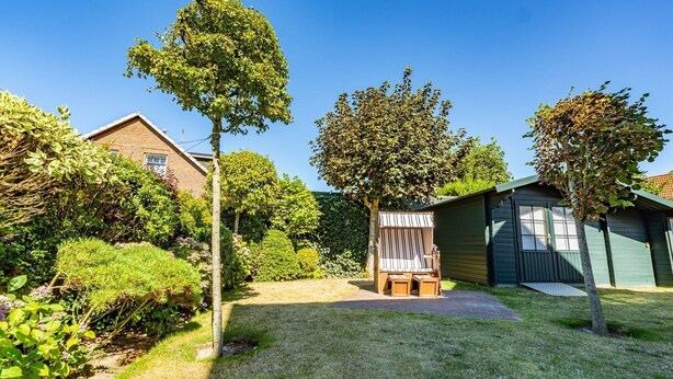 A backyard with a wooden deck, a shed, and a lawn. - House Lotte - Holiday home for up to 6 people with garden. - only 450m to the (Sylt)