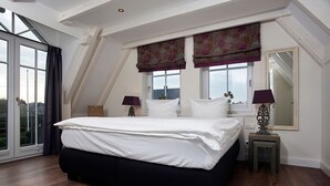 A bedroom with a large bed, two bedside tables, a window with curtains, and a view of the outside. - House Lotte - Holiday home for up to 6 people with garden. - only 450m to the (Sylt)