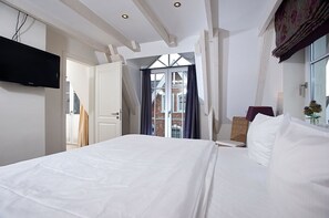 A hotel room with a large bed, a television mounted on the wall, and a view of the outside through a window. - House Lotte - Holiday home for up to 6 people with garden. - only 450m to the (Sylt)