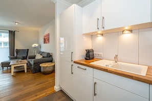 A modern kitchen with white cabinets, a wooden countertop, and a built-in sink.