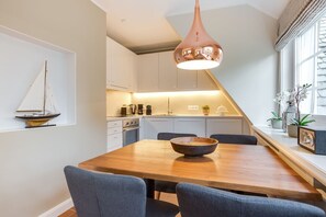 Una cocina moderna con armarios blancos, una mesa de comedor de madera y una lámpara colgante.